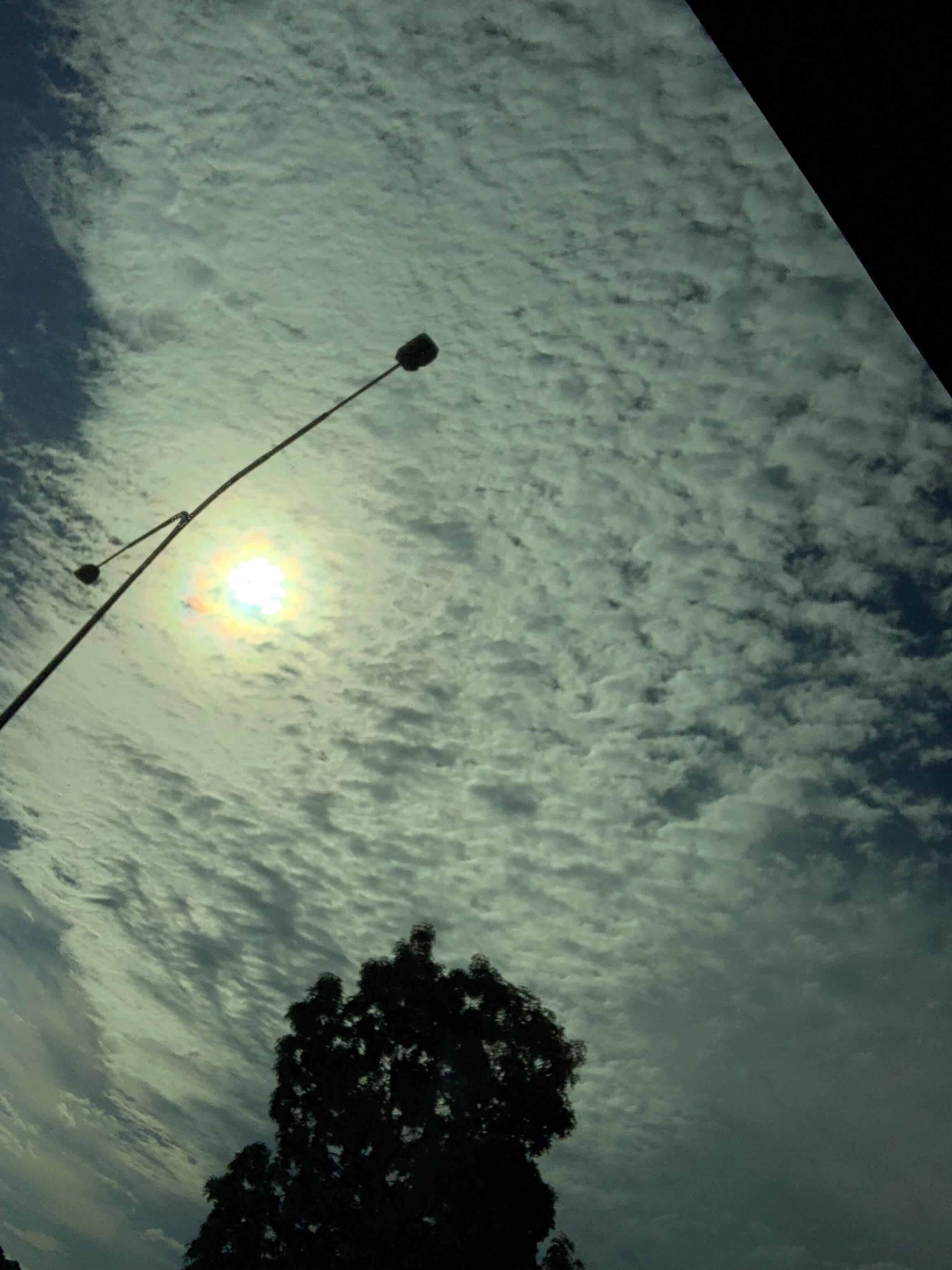 photo of the afternoon sun barely visible from behind a scaterring of clouds