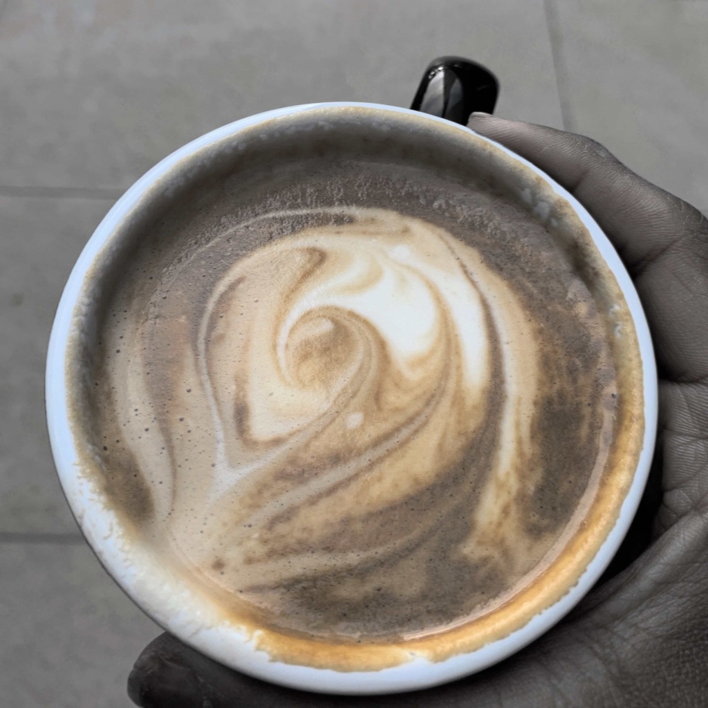 Close up photo of a cup of coffee with a swirling art. 