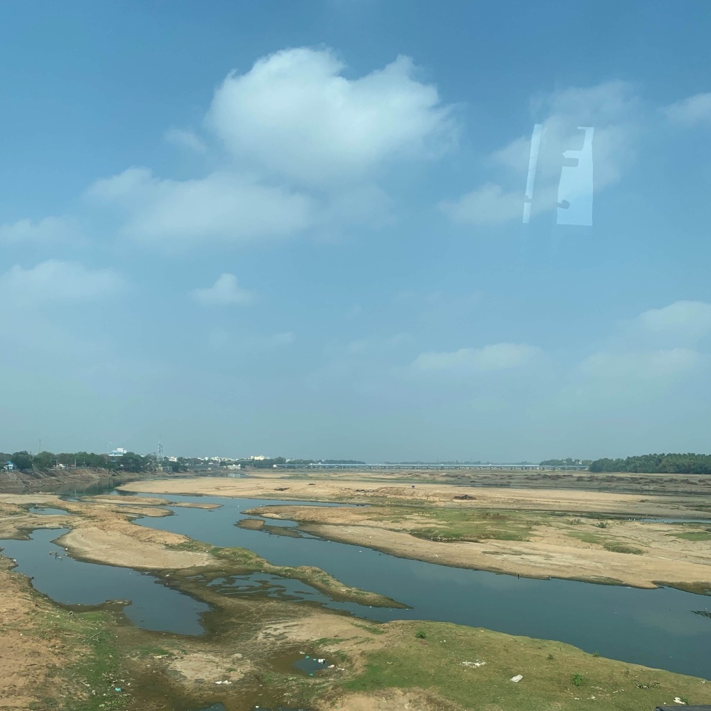 Photo of the Cauveri river in Trichy with spots of water. As seen through the window of a bus. 